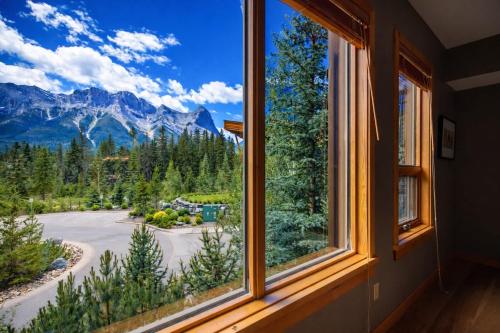 a window with a view of the mountains at Spring Creek Serenity at Rundle Cliffs Lodge in Canmore