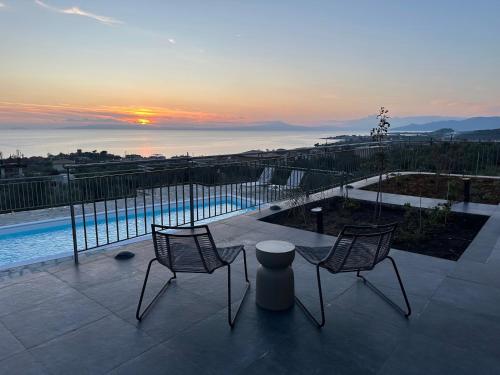 two chairs and a table on a patio with the sunset at Thalassori Villas in Agios Nikolaos