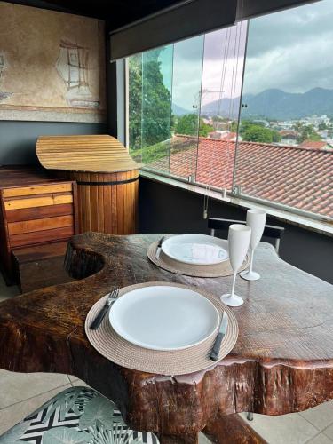 a wooden table with two plates and wine glasses on it at Espaço Verano- Master 1 in Niterói