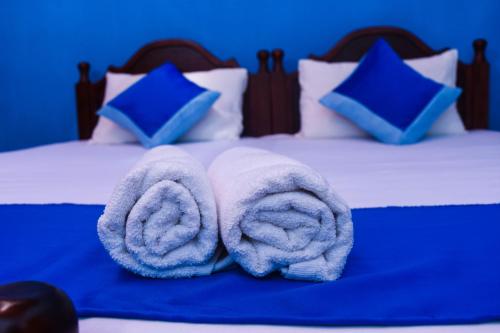Una cama con toallas blancas encima. en Shrine Inn en Kandy