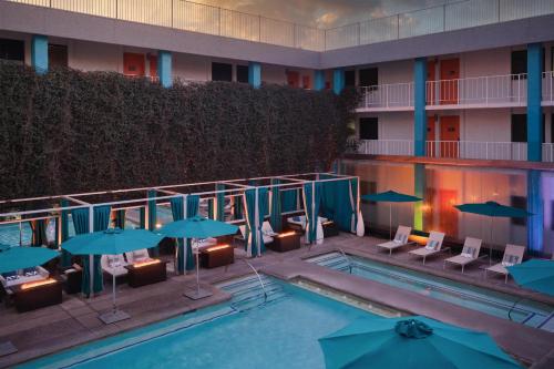 a swimming pool with chairs and umbrellas next to a hotel at The Clarendon Hotel & Spa, BW Signature Collection in Phoenix