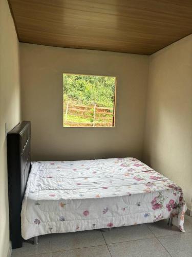 a small bedroom with a bed with a window at Chalé do Vicente in Ouro Preto