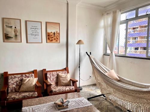 a hammock in a living room with two chairs and a window at Quarto Privativo na AvBeira mar - Apto familiar in Fortaleza
