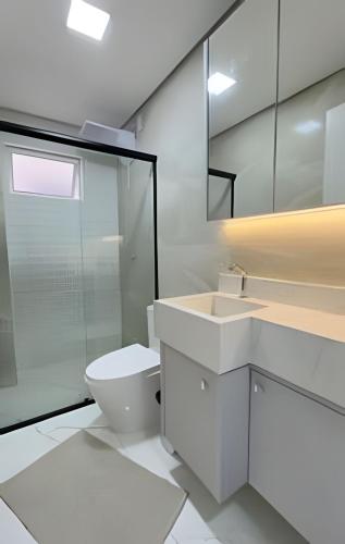 a white bathroom with a toilet and a glass shower at Apto Lavandas|2Qts.Lado Centro Eventos,150m Termas in Piratuba