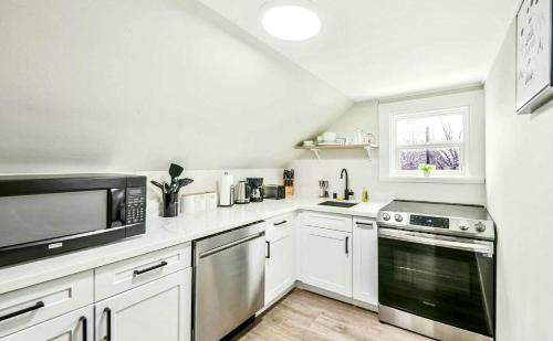a kitchen with white cabinets and stainless steel appliances at Charming & Bright Gem Prime Location Street Parking with AC in Renton