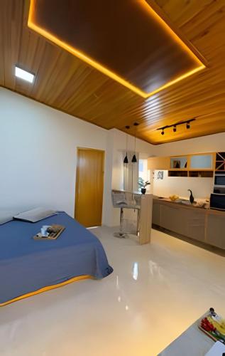 a bedroom with a bed and a desk and a kitchen at Suíte dos Sonhos-Climatizada,Hidromassagem,Garagem in Piratuba