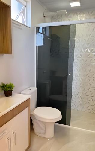 a bathroom with a toilet and a glass shower at Suíte dos Sonhos-Climatizada,Hidromassagem,Garagem in Piratuba