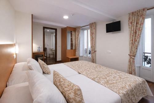a hotel room with a bed and a television at Hostal Anosa Casa in Santiago de Compostela