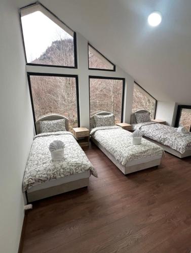 three beds in a room with large windows at Guest House Ropojan in Vusanje