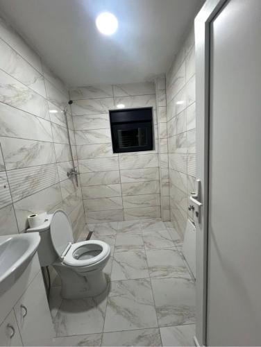 a bathroom with a toilet and a tv on the wall at Guest House Ropojan in Vusanje