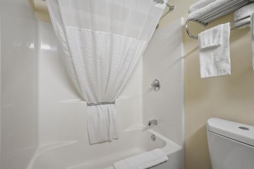a bathroom with a shower and a toilet and towels at Crossroads Hotel and Huron Event Center in Huron