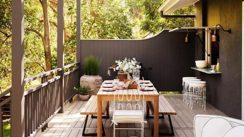 a patio with a wooden table and chairs at Designed By Three Birds Renovation in Pearl Beach