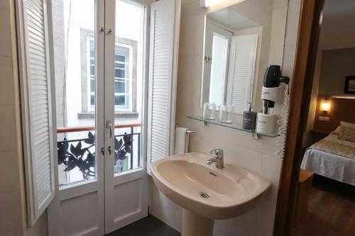 a bathroom with a sink and a window at Hostal Anosa Casa in Santiago de Compostela