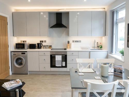 a kitchen with white cabinets and a table and chairs at Central 3 beds with parking in Reading