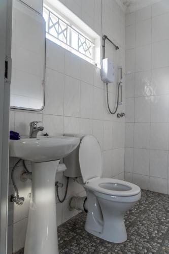 a white bathroom with a toilet and a sink at Timba Lodge in Blantyre