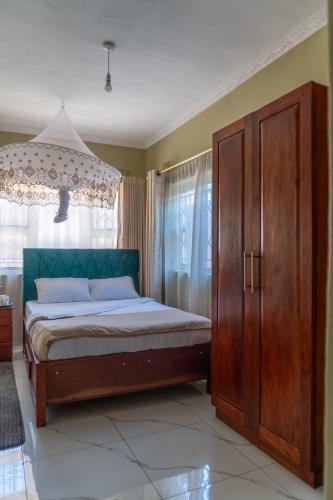 a bedroom with a bed and a wooden cabinet at Timba Lodge in Blantyre