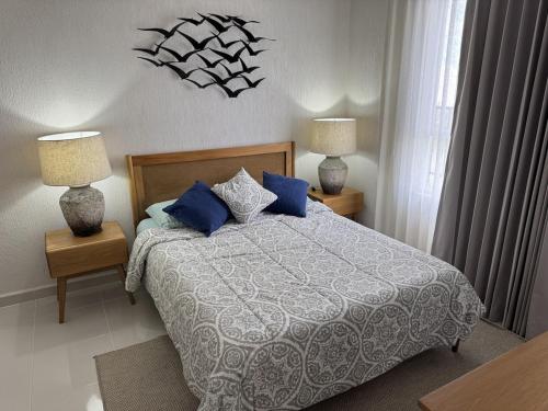 a bedroom with a bed with blue pillows and two lamps at Comfortable 2BR Condo pool & gym in Tulum