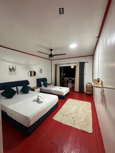 a bedroom with two beds and a red carpet at BIHING ANGAN water chalets in Semporna