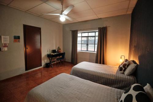 a bedroom with two beds and a window and a desk at Casa Arrayan in Guadalajara