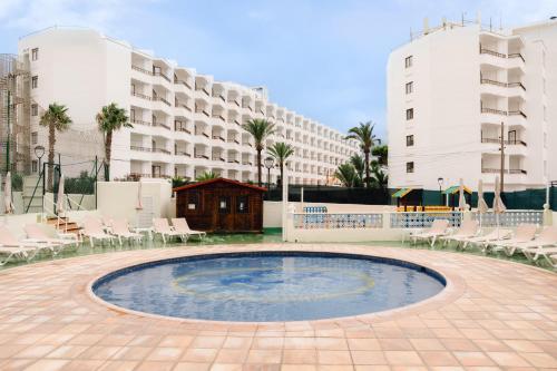 a pool in a courtyard with chairs and a building at BLUESEA Coral Beach in Es Cana