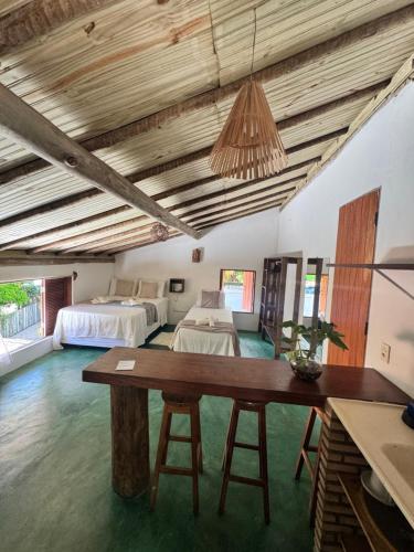 a bedroom with two beds and a table in a room at Pousada Lumawê Caraíva in Caraíva