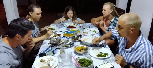 a group of people sitting around a table eating food at windy beach kite resort in Kalpitiya