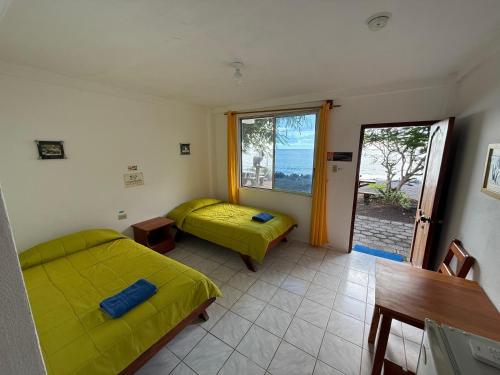 a room with two beds and a window with a view at Hotel Witttmer in Puerto Velasco Ibarra