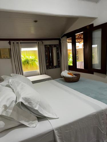 a bedroom with a large white bed with windows at Casa Cris in Itaúnas