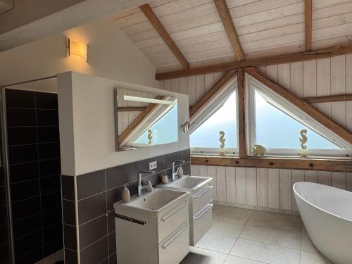 a bathroom with two sinks and a tub and a window at Lütt Marschkieker in Langenhorn