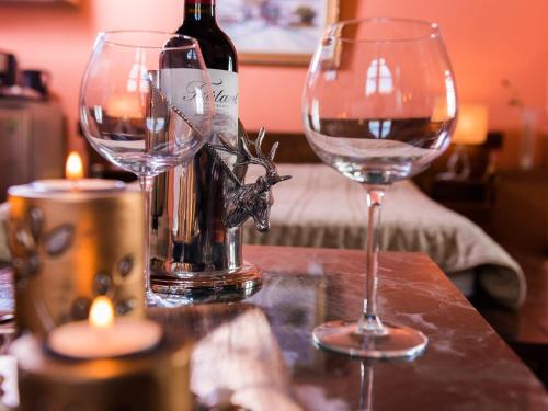 dois copos de vinho sentados numa mesa com uma garrafa de vinho em ViP Suite 4 Seasons em Arachova
