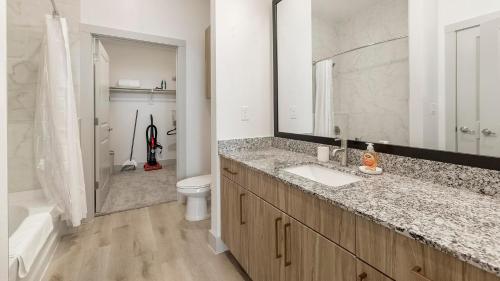 a bathroom with a sink and a toilet and a mirror at Landing Beautiful Studio Gym Pool in Addison
