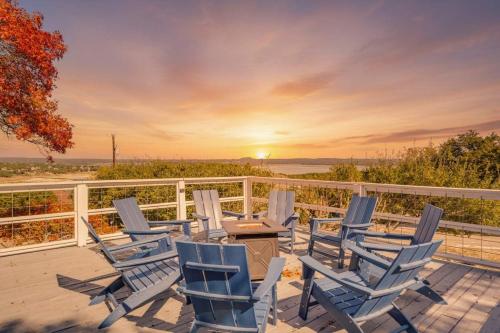 a deck with chairs and a table with the sunset at Tequila Sunrise hot tub lake view firepit pool in Canyon Lake