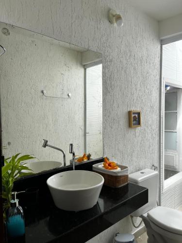 a bathroom with a sink and a toilet and a mirror at Casa Cris in Itaúnas