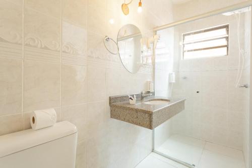 a white bathroom with a sink and a mirror at Pousada Barra Mar in Barra de Ibiraquera
