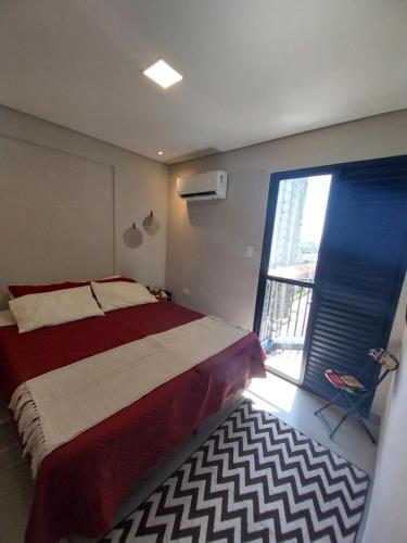 a bedroom with a bed and a large window at Prime Flat Palladium Mar & Piscina in São Vicente