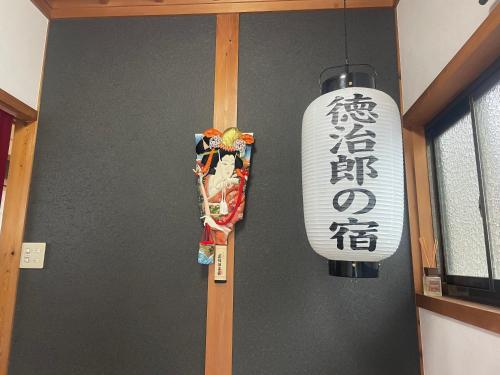a wall with a chinese sign and a light fixture at 徳治郎の宿 in Izumi-Sano
