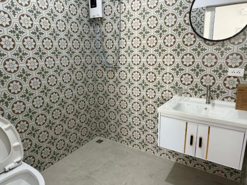 a bathroom with a toilet and a sink and a mirror at Roomz at Rawai in Ban Saiyuan (1)
