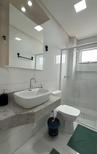 a white bathroom with a sink and a toilet at Apto Rosas| 3Q, todo Climatizado, Prox das Termas in Piratuba