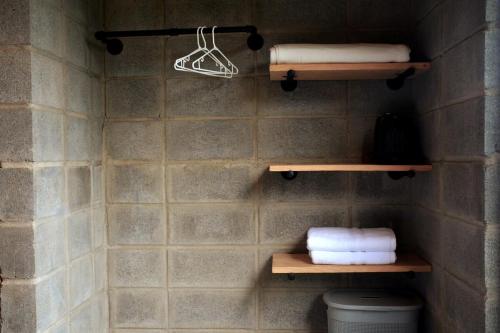 a bathroom with wooden shelves and towels on a wall at Private Mountain Cabin with Garden Views in Zarcero