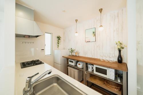 a kitchen with a sink and a refrigerator at 照間Terumaの美しい海と太陽 Soleが目前に広がる和室ありの宿 TERUSOLEテルソーレ in Uruma