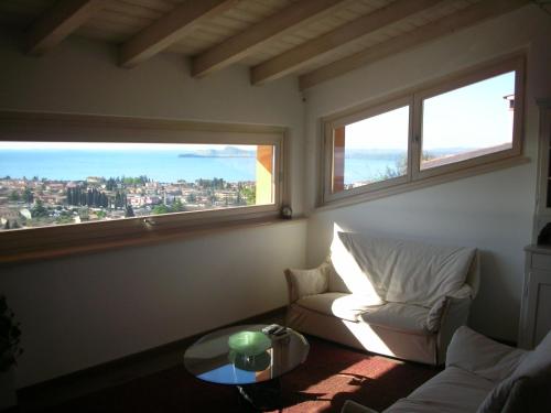 a living room with a couch and two windows at Villa Susina Casa Vacanze in Toscolano Maderno