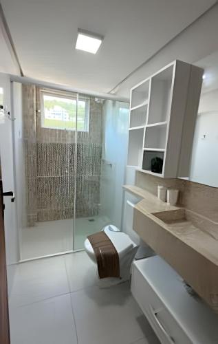 a bathroom with a toilet and a glass shower at Apto Copo Leite|3Q c|Sacada,Churrasqueira,na Aven in Piratuba