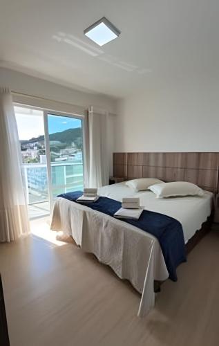 a bedroom with a large bed and a large window at Apto Copo Leite|3Q c|Sacada,Churrasqueira,na Aven in Piratuba