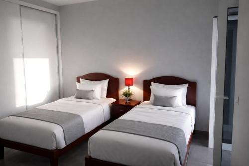 two beds in a hotel room with two lamps at Villa O Pomar with optional heated pool in Paul do Mar