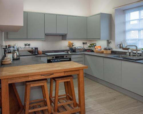 a kitchen with white cabinets and a wooden table at St Margarets Mews in Durham