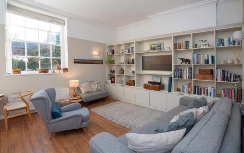 a living room with a couch and chairs and book shelves at St Margarets Mews in Durham