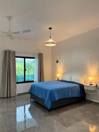 a bedroom with a blue bed and a window at Hotel Rincón Samaná in Las Galeras