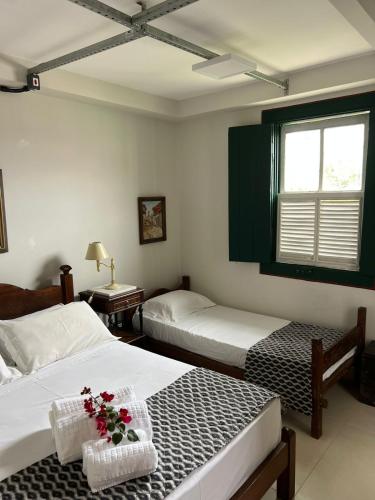 a bedroom with two beds and a window with flowers at Loft Macau in Diamantina