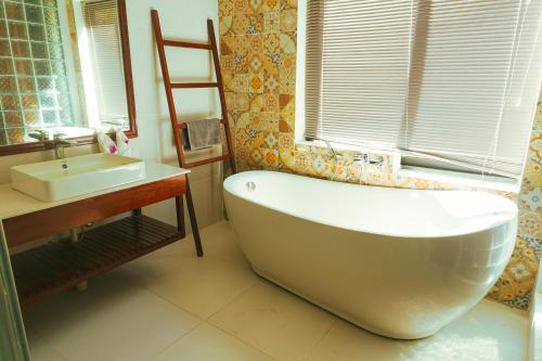 a bathroom with a white tub and a sink at Kakse Teschor Mong Reththy Senchey in Phumĭ Svay Dângkum