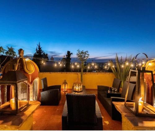 a rooftop patio with a fireplace and furniture and lights at Casa Mesones in San Miguel de Allende